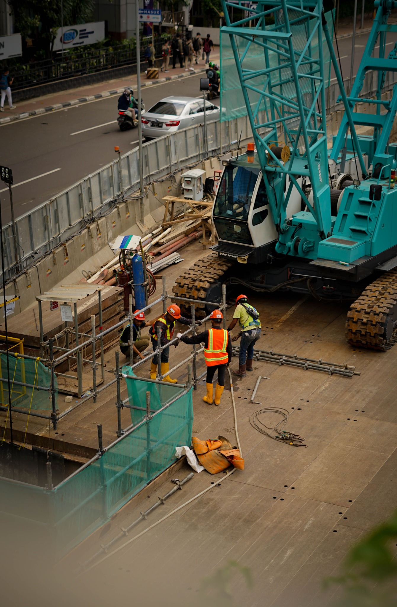 Construction workers beside a crawler crane